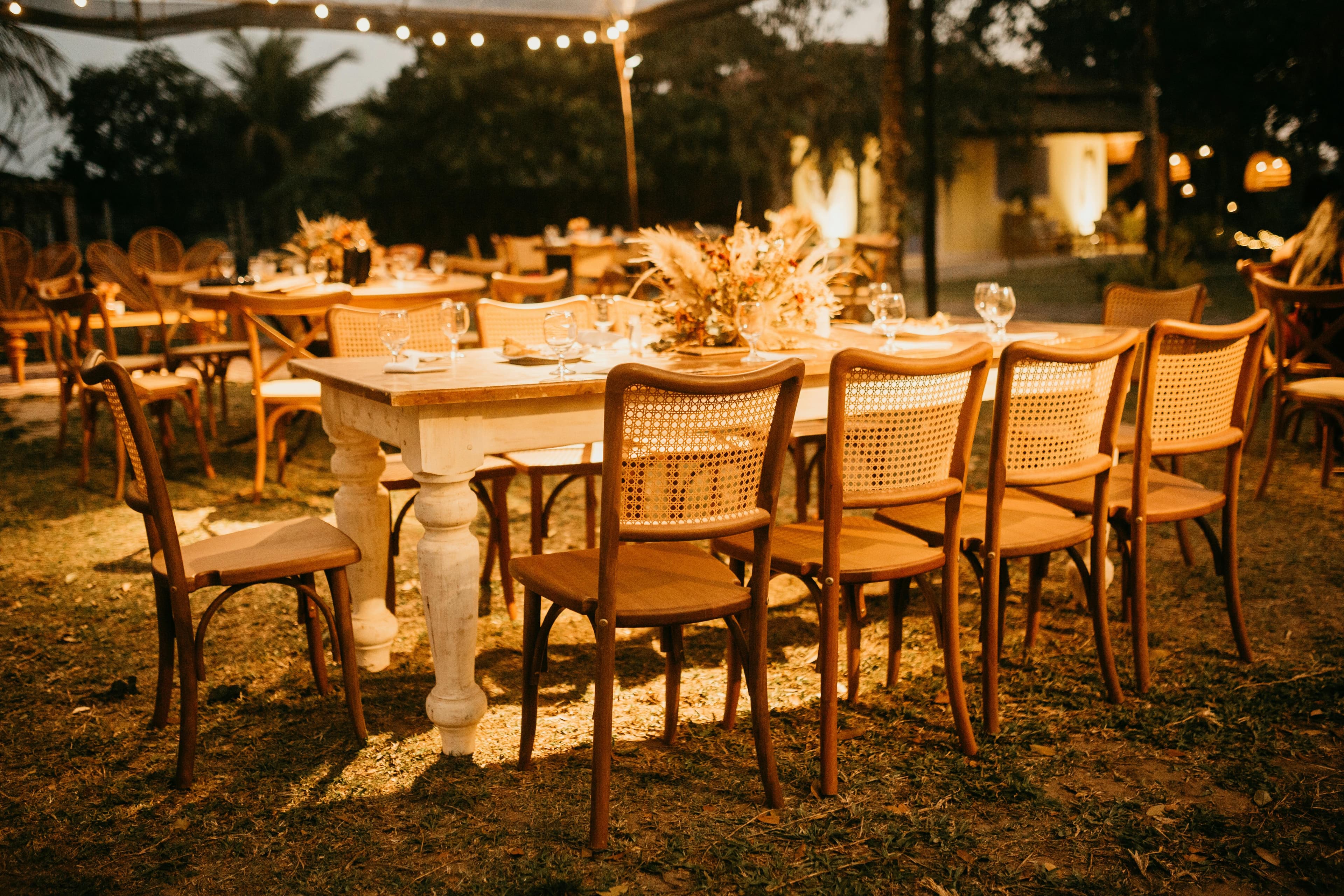 Warm beleuchtete Hochzeitstafel unter Lichterketten im Freien