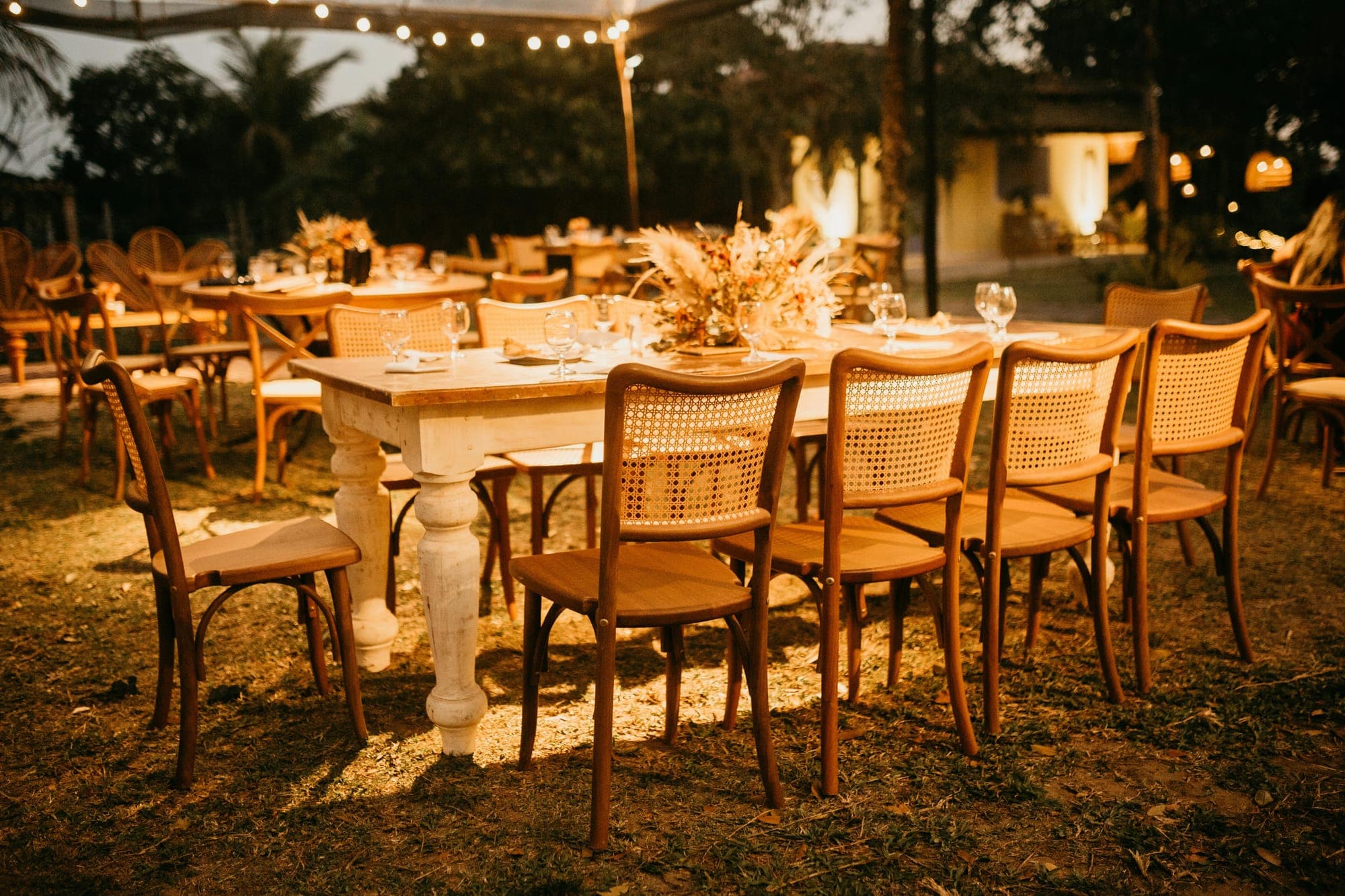Warm beleuchtete Hochzeitstafel unter Lichterketten im Freien